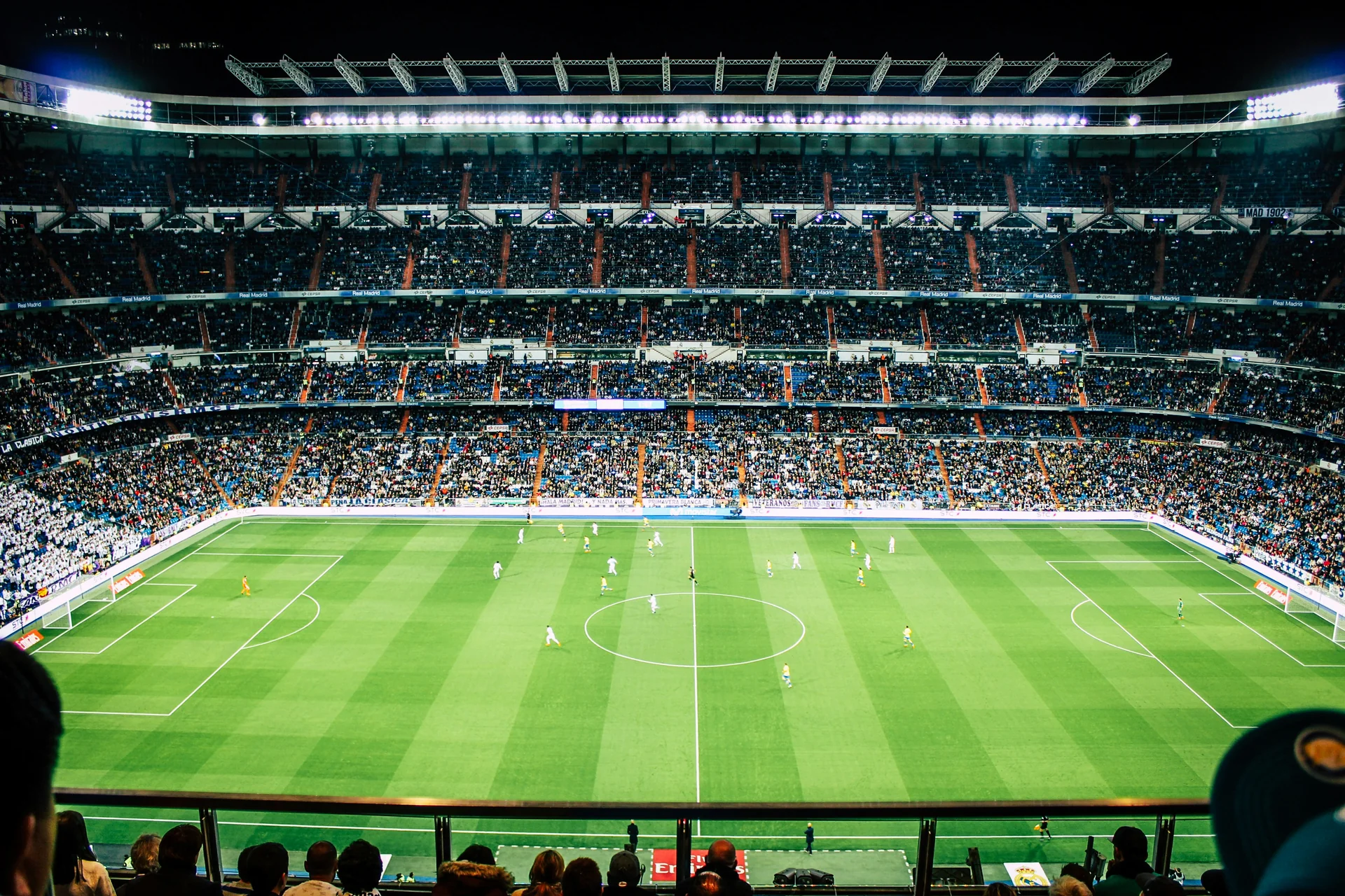 A packed football stadium under floodlights during a night match